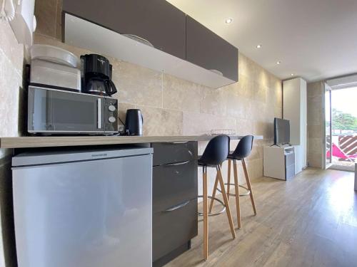 uma cozinha com um balcão com um micro-ondas e bancos em Appartement La Baule, 1 pièce, 2 personnes - FR-1-245-107 em La Baule