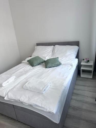 ein Bett mit weißer Bettwäsche und grünen Kissen darauf in der Unterkunft Przytulny apartament in Szczecinek