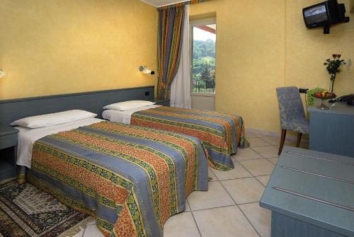 a hotel room with two beds and a window at Hotel Ristorante del Peso in San Michele Mondovì