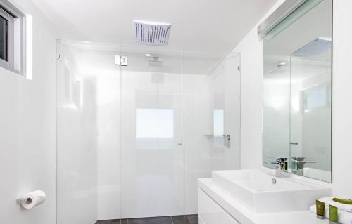 a white bathroom with a sink and a shower at 28 Park Crescent, Sunshine Beach in Noosa Heads