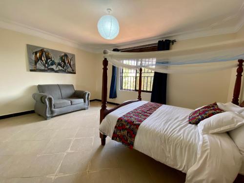 a bedroom with a bed and a chair and a couch at The Fortuna Hotel and Cafe in Kabale