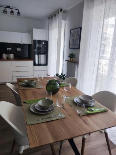 a wooden table with plates and wine glasses on it at 2 Appartements au Centre d'EVRY proches de PARIS in Evry-Courcouronnes