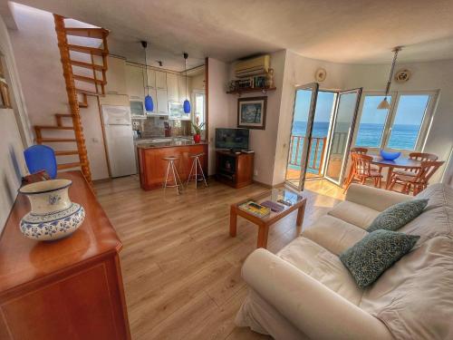 a living room with a couch and a kitchen with the ocean at Apartamento en acantilado con wifi y aire acondicionado in Sitges