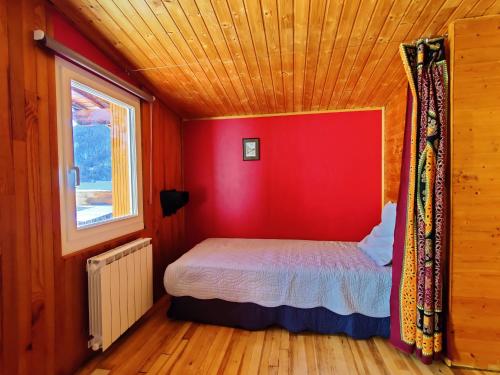 ein Schlafzimmer mit einer roten Wand und einem Bett in einem Zimmer in der Unterkunft Chalet Ailleurs Appartement à Molines en Queyras in Molines-en-Queyras