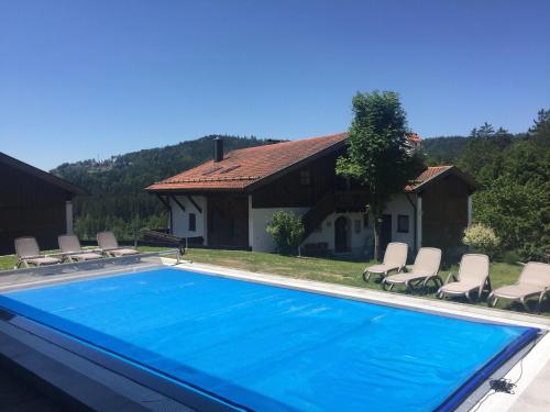 uma piscina com cadeiras e uma casa em SIMPLY-THE-BEST-Ferienwohnung-mit-Pool-Sauna-Schwimmbad-bis-6-Personen em Hauzenberg