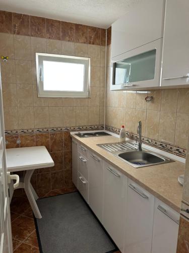 Elle comprend une petite cuisine avec un évier et une fenêtre. dans l'établissement Apartments Edona, à Ulcinj