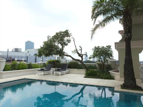 a swimming pool with two chairs and a palm tree at Hotel Gran Mahakam in Jakarta