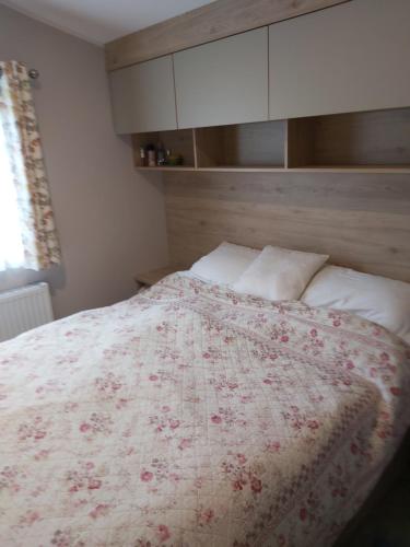 a bedroom with a bed with a red and white blanket at Wood Farm Holiday Park in Charmouth