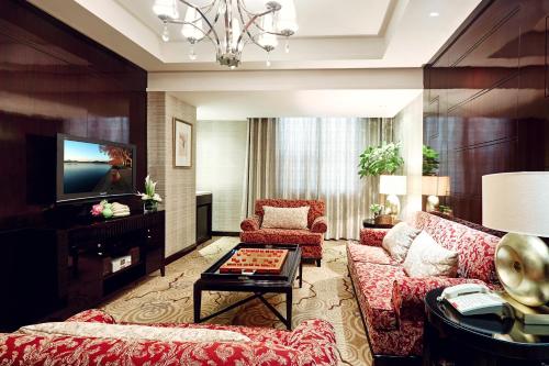 a living room with a couch and a tv at Huachen International Hotel in Hangzhou