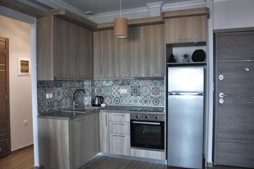 uma cozinha com armários de madeira e um frigorífico de aço inoxidável em SKYLINE Fine Living em Neoi Poroi