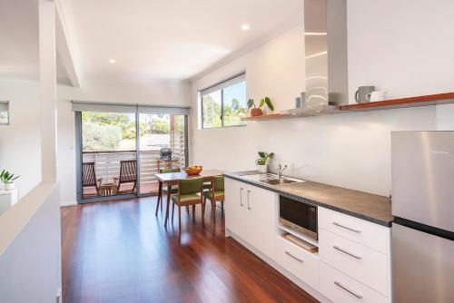 a kitchen with white cabinets and a table with chairs at Karri Tree Studio Apartment in Margaret River Town