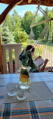 une table avec un pot de limonade en verre et une balançoire dans l'établissement Gościniec Joanna, à Rajgród