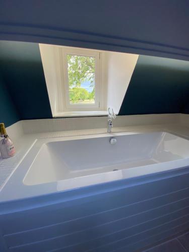 a white tub in a bathroom with a window at Charme rustique- piscine privée et jardin in Queyssac