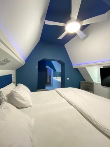 a bedroom with a white bed with a ceiling fan at Charme rustique- piscine privée et jardin in Queyssac