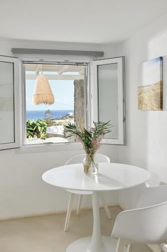 a white table and chairs in a room with a window at VLIA MAR Myconian Residences in Kalafatis