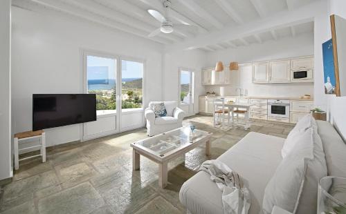 a white living room with a couch and a tv at VLIA MAR Myconian Residences in Kalafatis