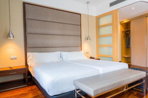 a bedroom with a large white bed and a bench at Hotel Compostela in Santiago de Compostela