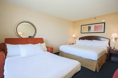 a hotel room with two beds and a mirror at Courtyard by Marriott Flint Grand Blanc in Flint