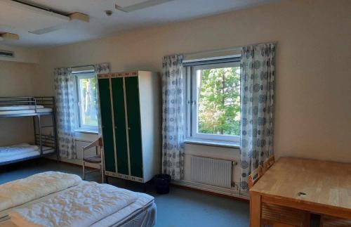 a bedroom with a bed and two windows at Mäshult Kurs & Lägergård in Skällinge