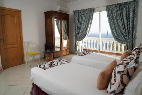 sypialnia z 2 łóżkami i dużym oknem w obiekcie Riad Ras Lafaa w mieście Safi