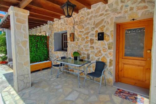 a patio with a table and chairs on a stone wall at MyrillasHome in Lefkímmi