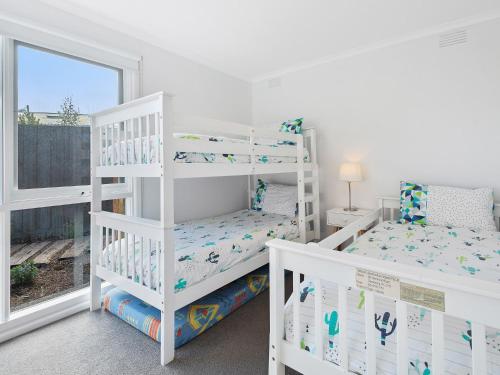 a white bedroom with two bunk beds and a window at Rye Beach And Pool House by Ready Set Stay in Rye