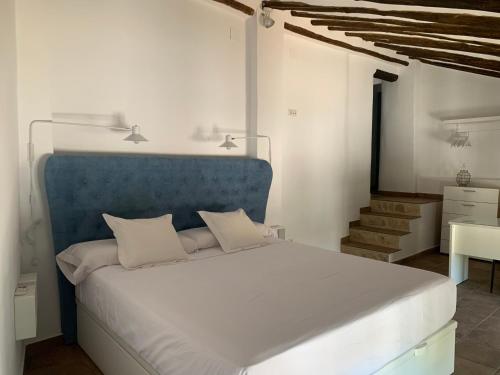 a bedroom with a large bed with a blue headboard at Casa Genilla in Priego de Córdoba