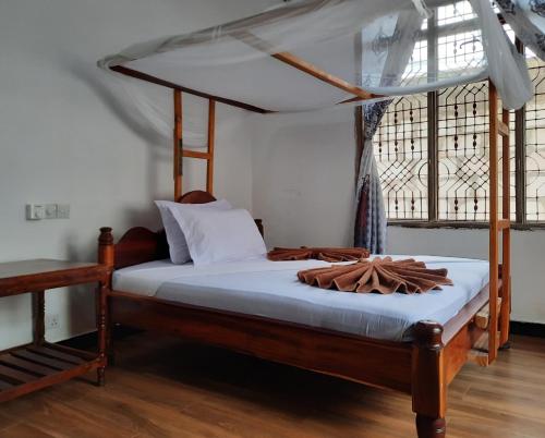 a bedroom with a wooden bed with a canopy at Kajificheni House in Nungwi
