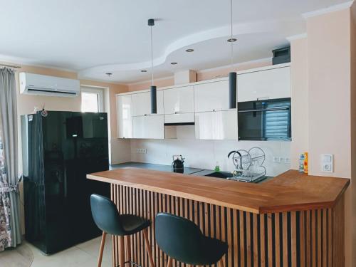a kitchen with white cabinets and a black refrigerator at Apartament comfort in Pisz