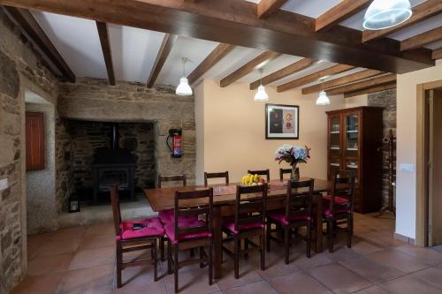 una sala da pranzo con tavolo, sedie e camino di Casa rural completa Río Sarela a Santiago de Compostela
