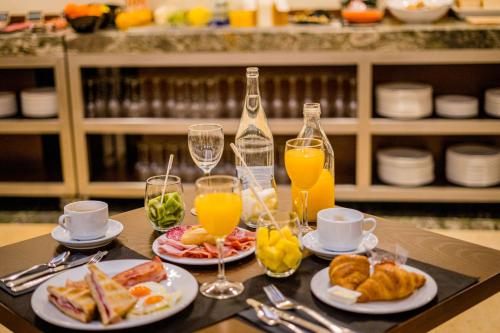 a table with plates of food and glasses of orange juice at Hotel Compostela in Santiago de Compostela