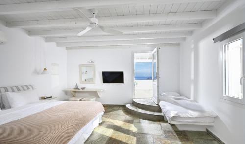 a white bedroom with a bed and a window at VLIA MAR Myconian Residences in Kalafatis