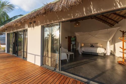 a master bedroom with a bed and a deck at Kumba Lodge in Praia do Tofo