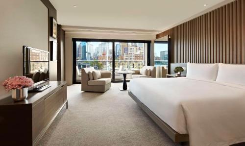 a bedroom with a large bed and a living room at Park Hyatt Sydney in Sydney