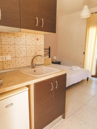 a kitchen with a sink and a bed in a room at Aroma Studios and Apartments in Vourvourou