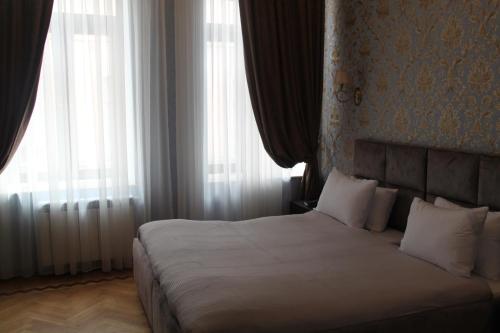 a bedroom with a bed with white sheets and windows at Hotel 1883 in Baku