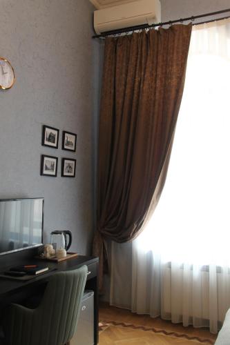 a room with a curtain and a desk and a television at Hotel 1883 in Baku