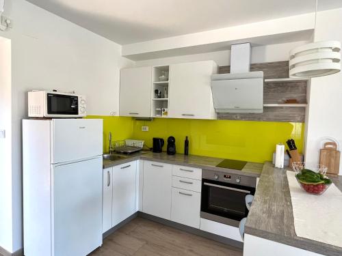 eine Küche mit weißen Geräten und gelben Wänden in der Unterkunft Katarina in Primošten