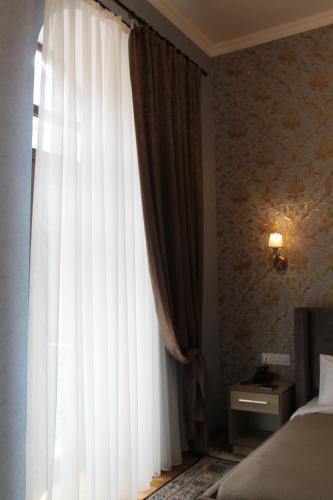 a bedroom with a bed and a window with curtains at Hotel 1883 in Baku