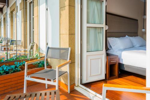 a room with a bed and a chair on a balcony at Hotel Compostela in Santiago de Compostela