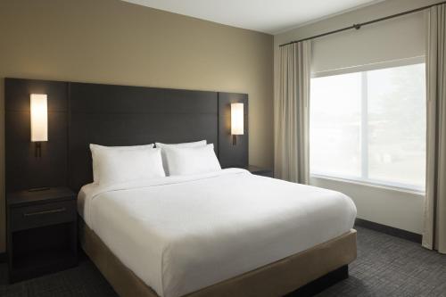 a large white bed in a hotel room with a window at Residence Inn by Marriott Jonesboro in Jonesboro