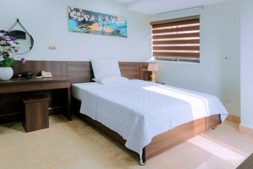 a bedroom with a bed and a desk and a window at Thu Ha Hotel in Uông Bí