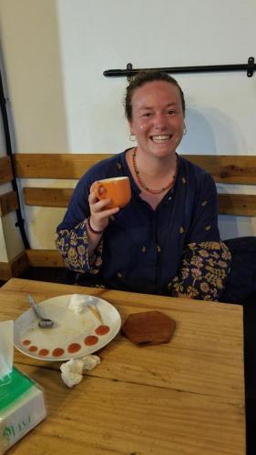 a woman sitting at a table holding a cup at CoffeeBunk Hostel in Tangerang