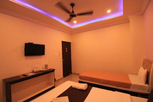 a small room with a bed and a tv at Bouvana Residency in Puducherry