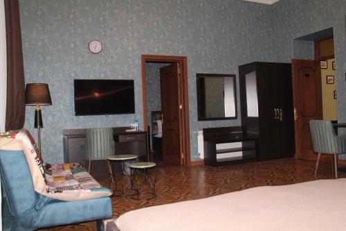 a room with a bed and a chair and a tv at Hotel 1883 in Baku