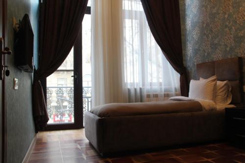 a bedroom with a bed and a window with a balcony at Hotel 1883 in Baku