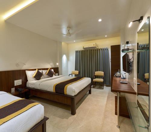 a hotel room with two beds and a desk at Hotel Fortune Inn in Kolhapur