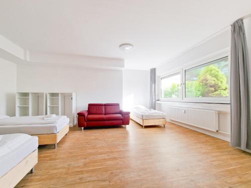 a white room with two beds and a red chair at Tolstov Apartments - 1 or 3 Room Apartments with Balcony - 20 Min Messe DUS & Airport DUS in Meerbusch