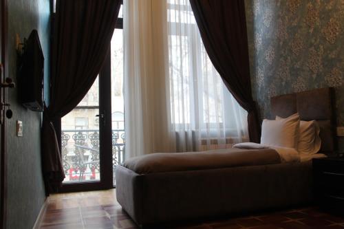 a bedroom with a bed and a large window at Hotel 1883 in Baku