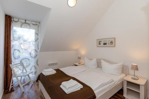een witte slaapkamer met een bed en een raam bij Ferienwohnung W16 3 S in Graal-Müritz